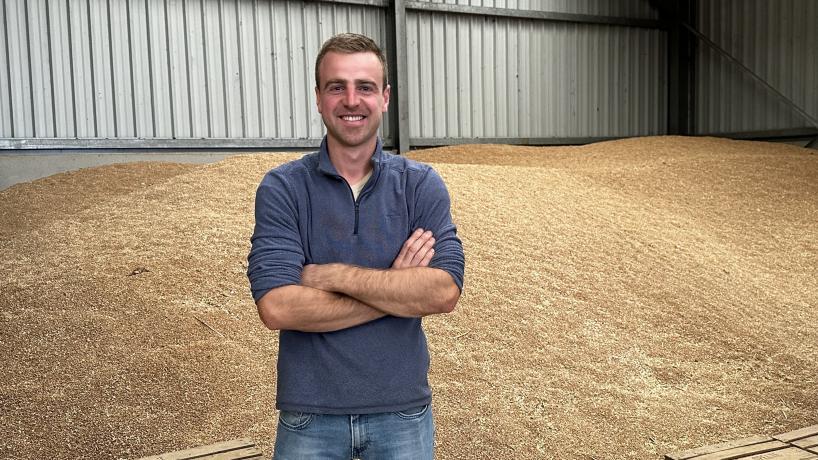 Damien Tilkin posant devant des céréales entreposées