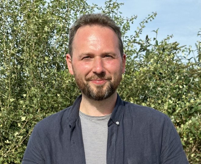 En plein air, plan rapproché taille de François, responsable communication chez Terres Vivantes, souriant face caméra